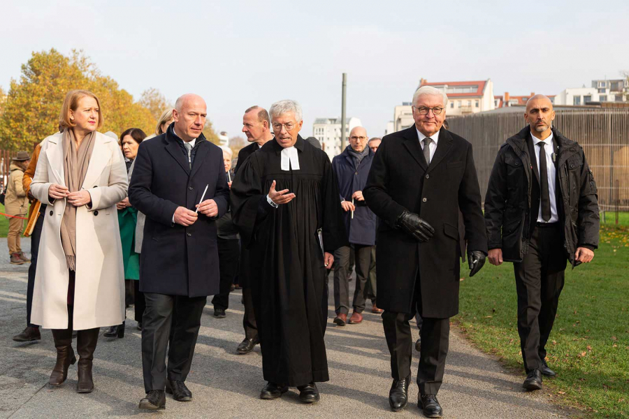 in Gruppe von Personen läuft über das Gelände der Gedenkstätte Berliner Mauer. Im Vordergrund sind die in der Bildbeschreibung genannten Personen.